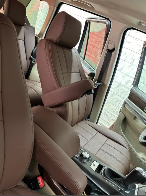 Front driver and passenger seats covered in custom brown artificial nappa leather with armrest, showing precision fit and stitching