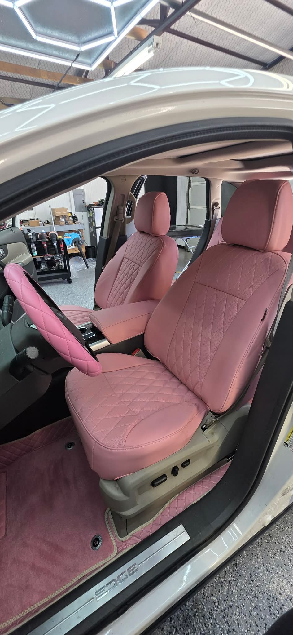 Front seats and steering wheel of a 2013 Ford Edge with custom light pink artificial Nappa leather seat covers and matching steering wheel cover