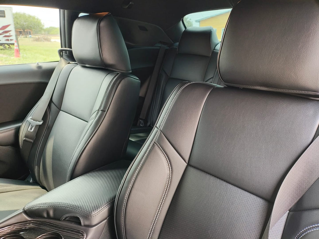 Close-up view of custom fit black artificial nappa leather seat covers on front seats of a 2021 Dodge Challenger showing smooth texture and white stitching