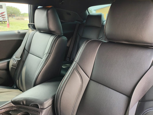 Close-up view of custom fit black artificial nappa leather seat covers on front seats of a 2021 Dodge Challenger showing smooth texture and white stitching