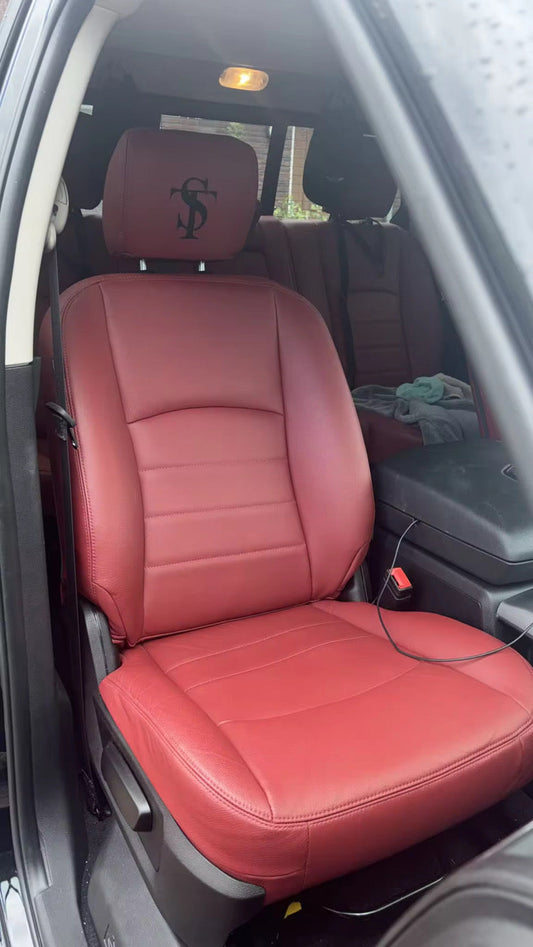 Close-up of burgundy artificial Nappa leather front seat cover with embroidered TS logo on headrest in 2024 RAM 1500