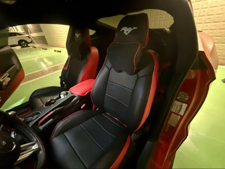 Front seats of a Mustang Coupe fitted with custom black and red seat covers and embroidered Mustang logo on the headrests