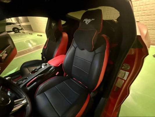 Front seats of a Mustang Coupe fitted with custom black and red seat covers and embroidered Mustang logo on the headrests