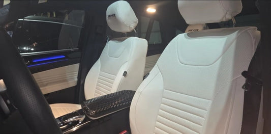 Front seats of a Mercedes Benz GLE covered in white artificial nappa leather seat covers with detailed stitching
